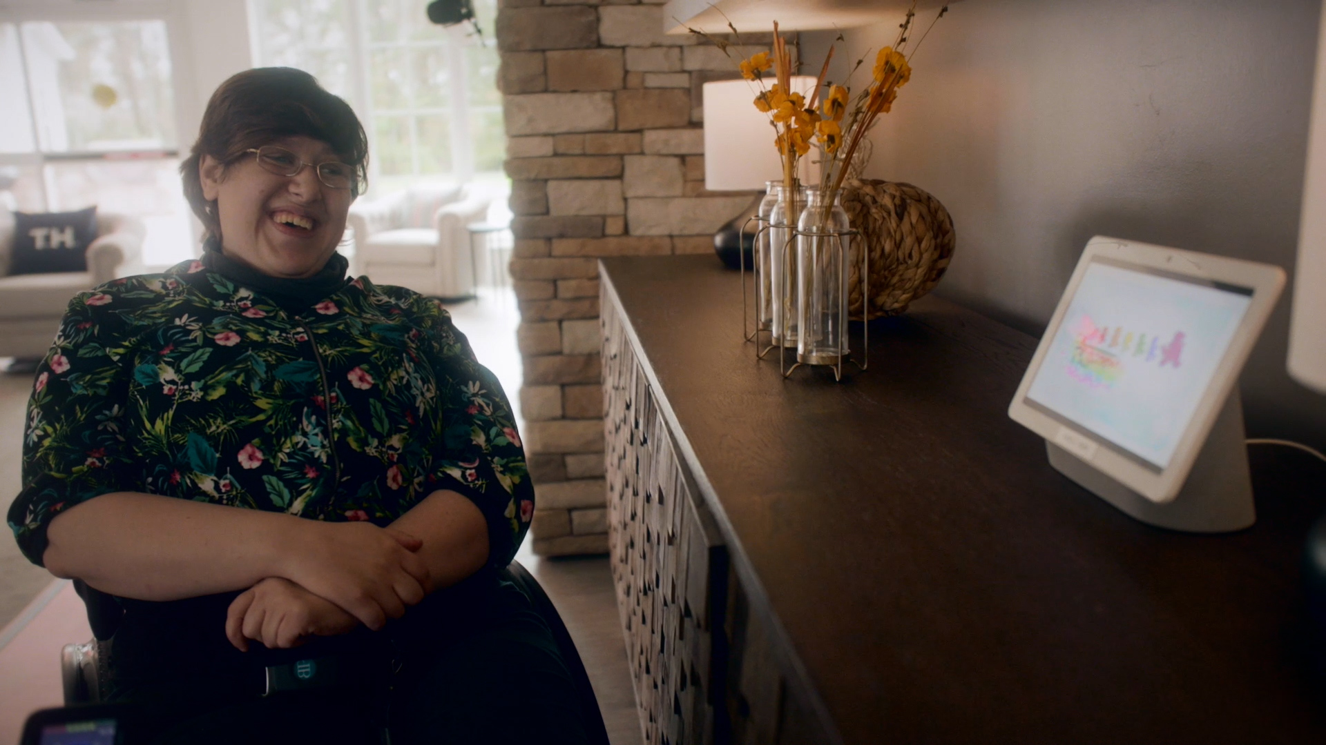 Champions Place Resident laughs in front of a Google Nest Hub screen placed on a table
