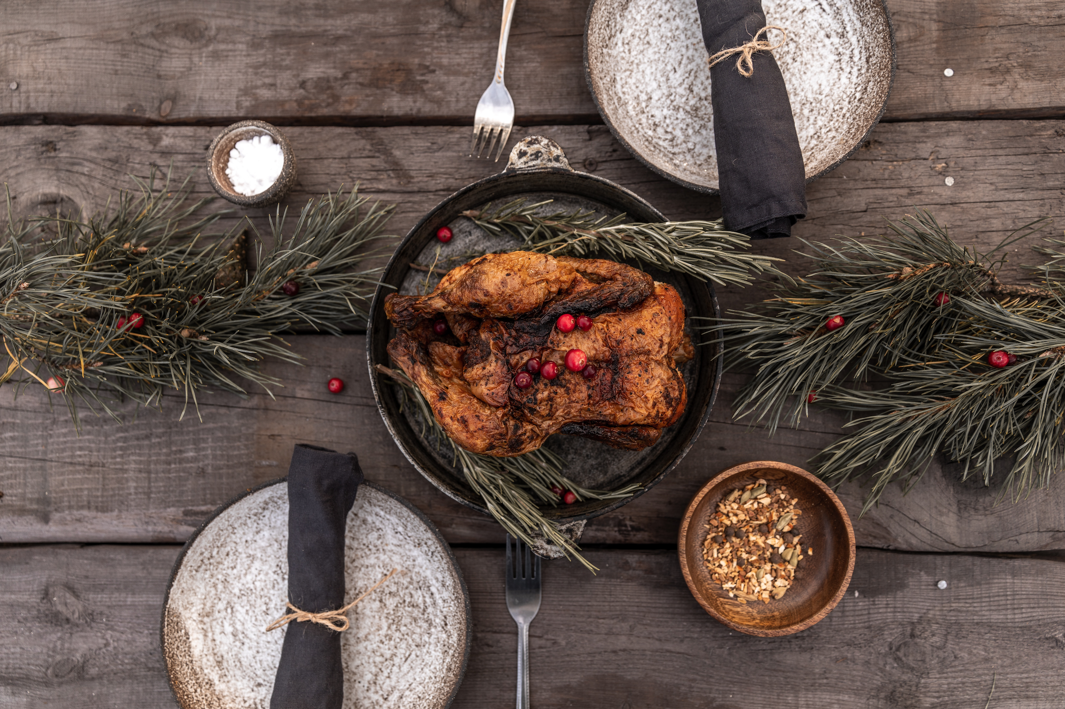 A table setting for two with holly and a roast turkey