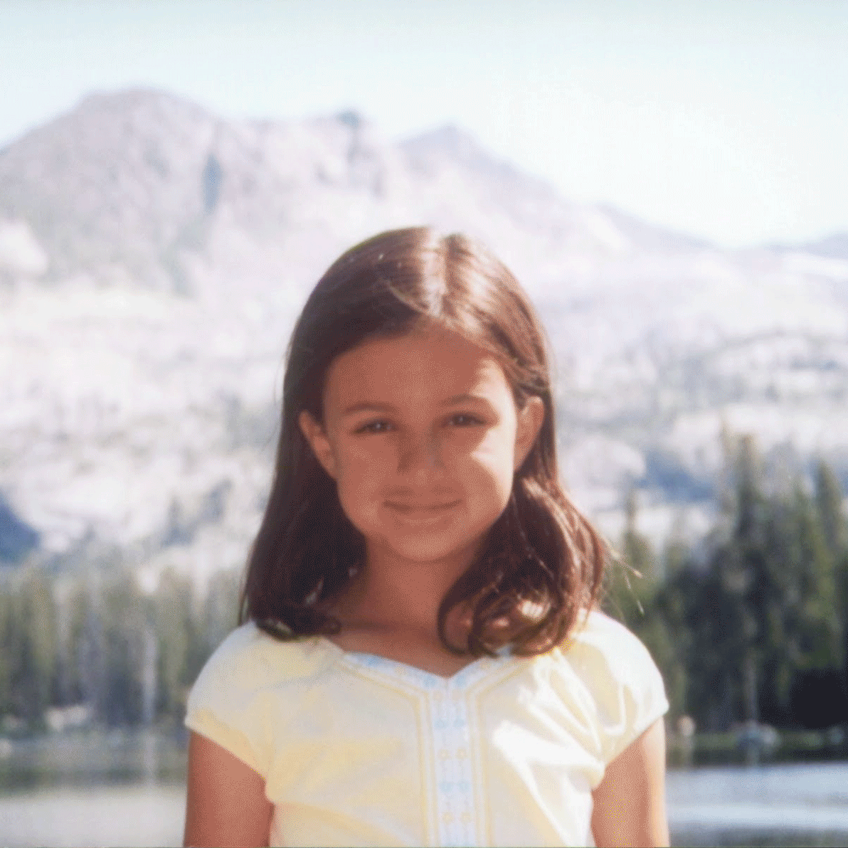Ein vor Jahren aufgenommenes, verschwommenes Foto eines kleinen Mädchens vor einer Berglandschaft wird mit dem Google Fotos-Feature „Scharfzeichnen“ in diesem GIF schärfer