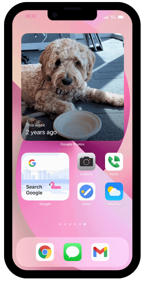 An iPhone 13 screen with a pink background showing a user cycle through a Smart Stack of Google widgets.