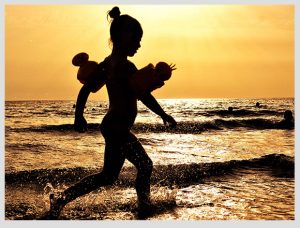 niña jugando en el mar al atardecer