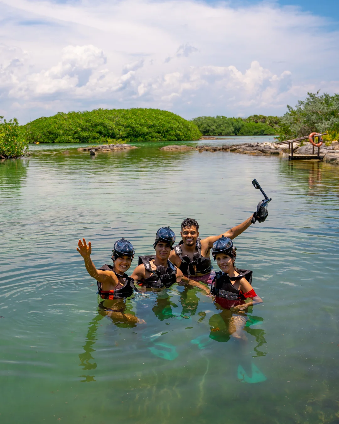 Personas saludando a cámara en laguna Yal-Kú usando el equipo de snorkel completo