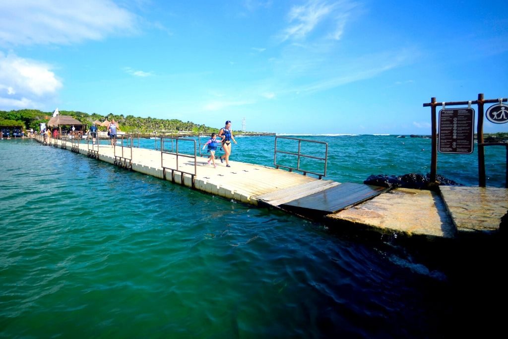 personas cruzando por puente flotante de xel-há