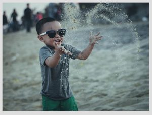 niño con lentes de sol jugando con arena