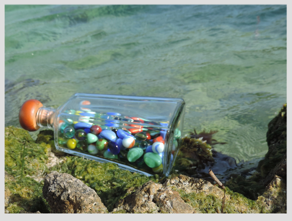 botella con canicas junto al mar