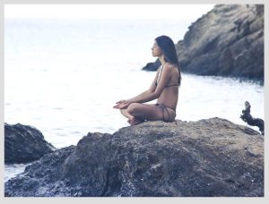 mujer haciendo yoga frente al mar