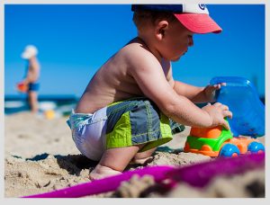 niño jugando con arena en la playa