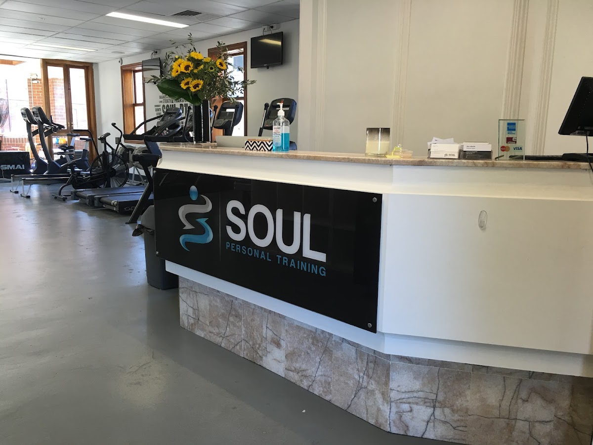 The photo shows the reception area of a fitness business with a branded counter and a few spin bikes visible in the background.