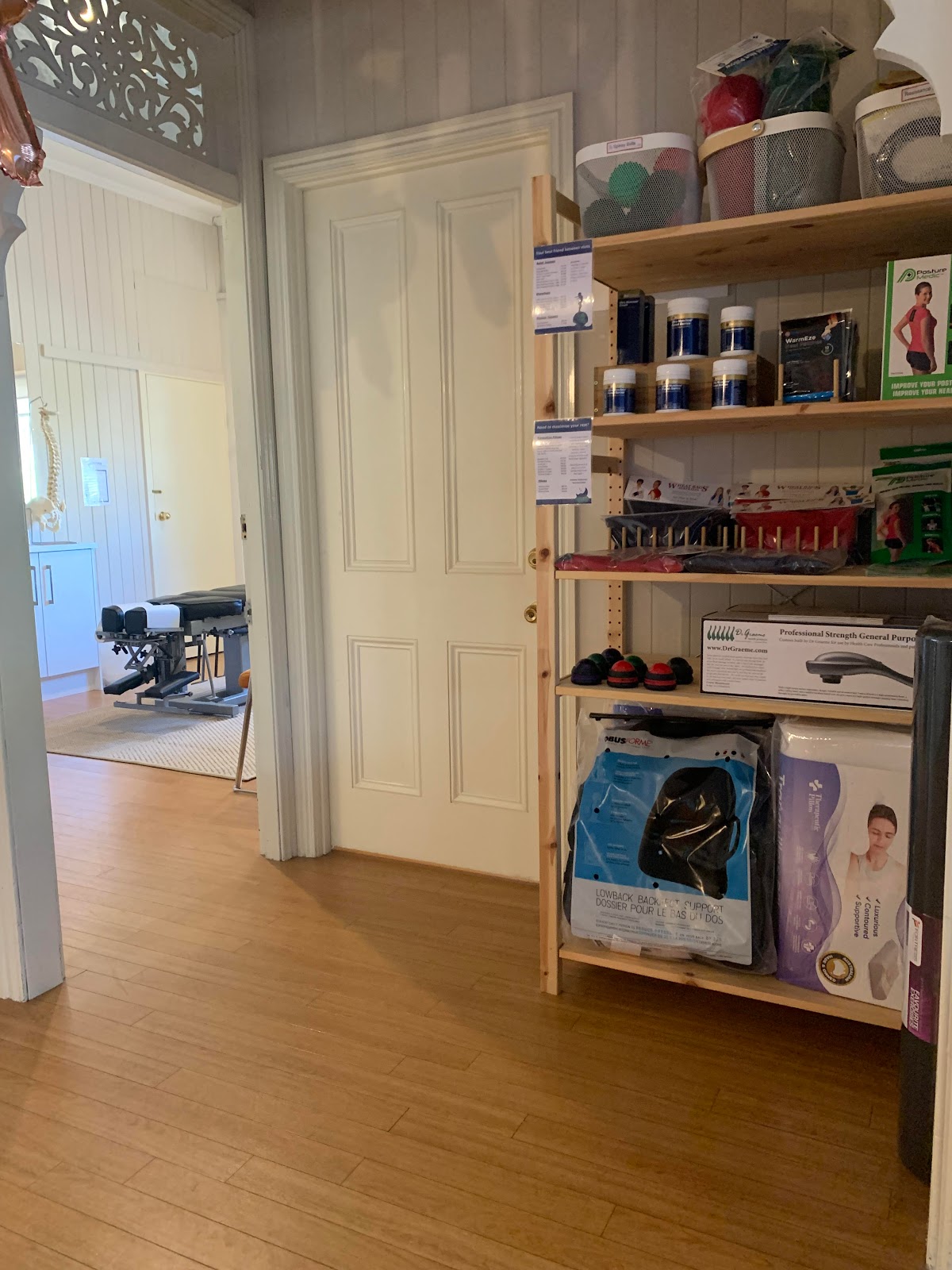 The photo shows a clinical-looking studio with shelves full of medical supplies and recovery equipment, including free weights and recovery boots.