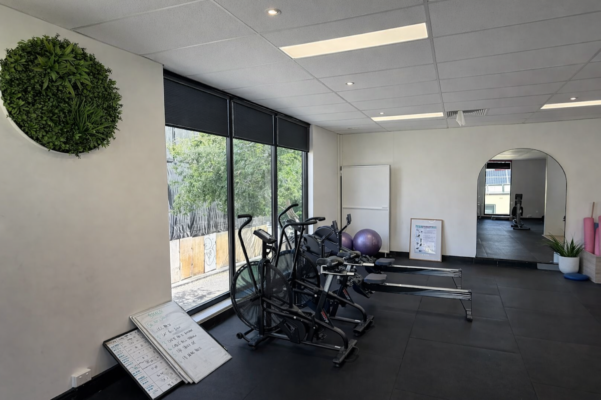 The photo shows a clean and minimalist gym interior with several spin bikes and free weights.