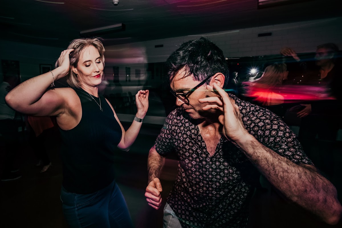 A group of people are dancing and having fun in a dimly lit space, seemingly participating in a fitness-related event.