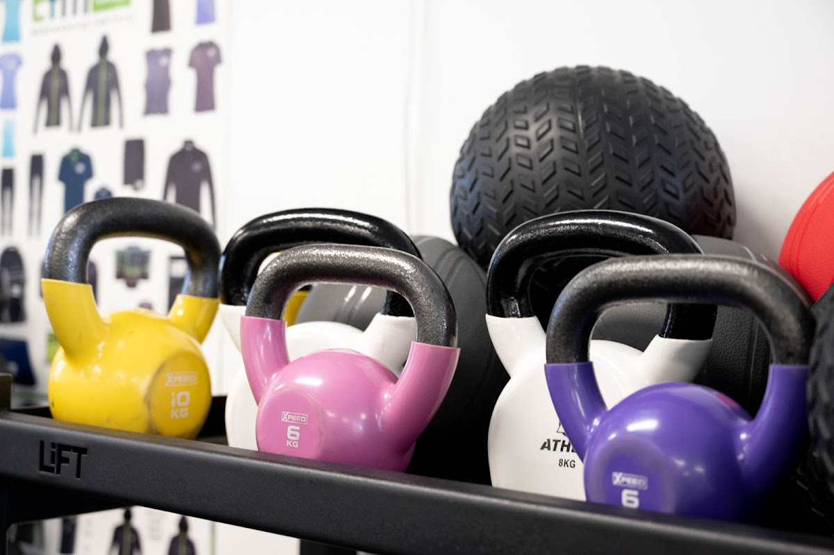 A close-up shot showcases a rack filled with colorful kettlebells of varying weights.