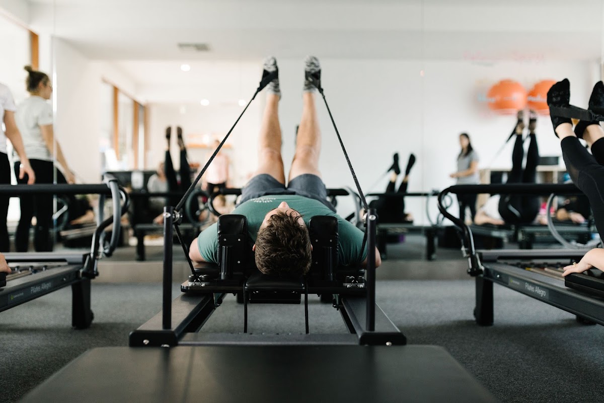 A group of people are participating in a Pilates class using reformer machines.