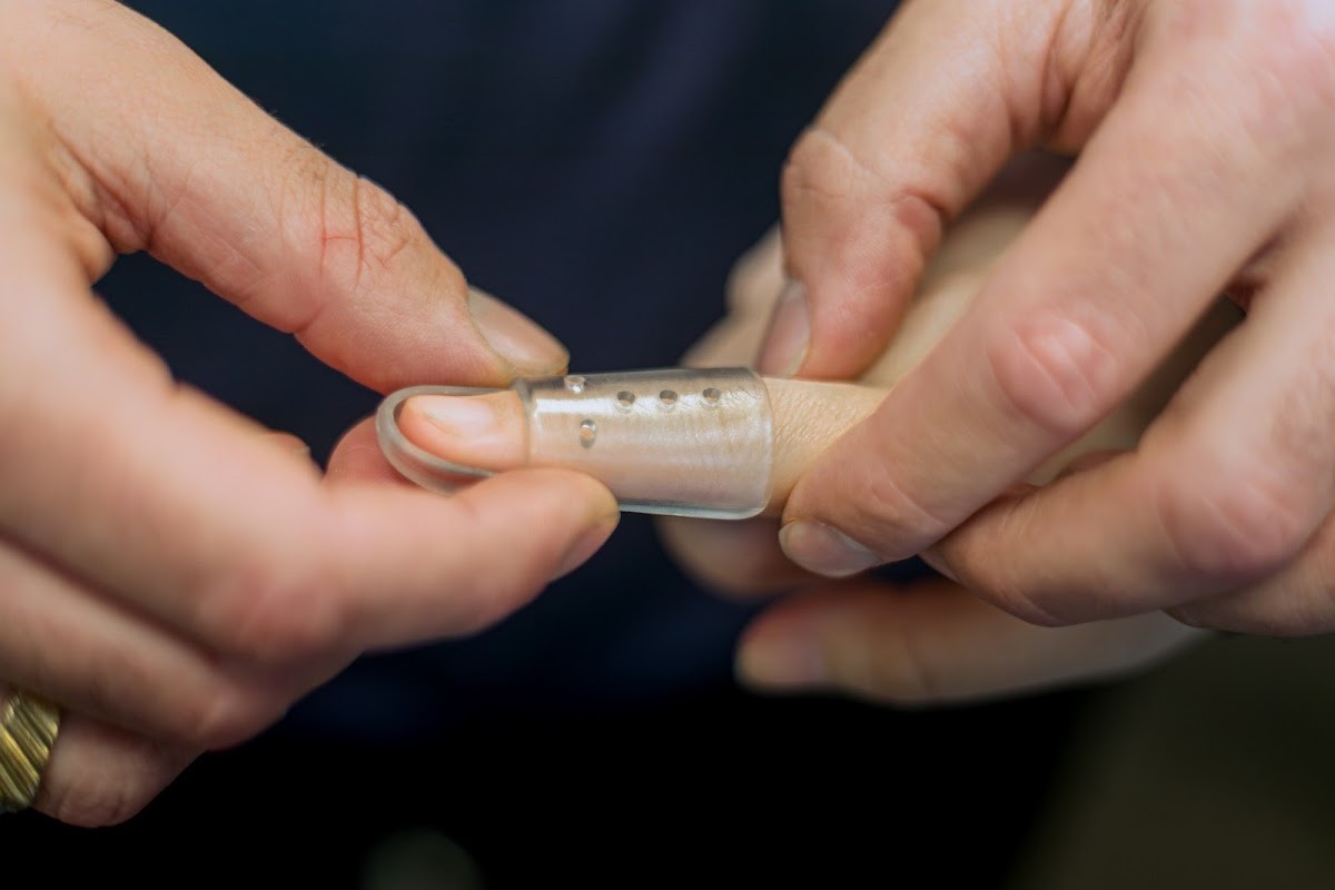 A close-up shot shows hands holding a glass infrared sauna capsule.