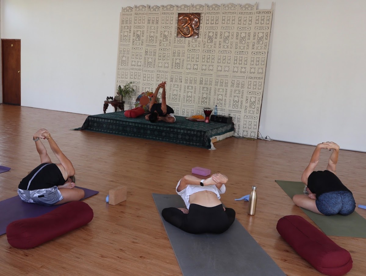 A yoga studio scene shows a few participants in poses with a trainer guiding them.