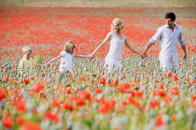 A family enjoying a walk through a field of poppies, suggesting an outdoor fitness activity or lifestyle.