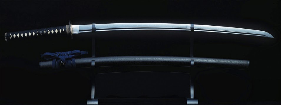 The photo showcases a katana, a traditional Japanese sword, displayed on a wooden stand in a dimly lit setting.