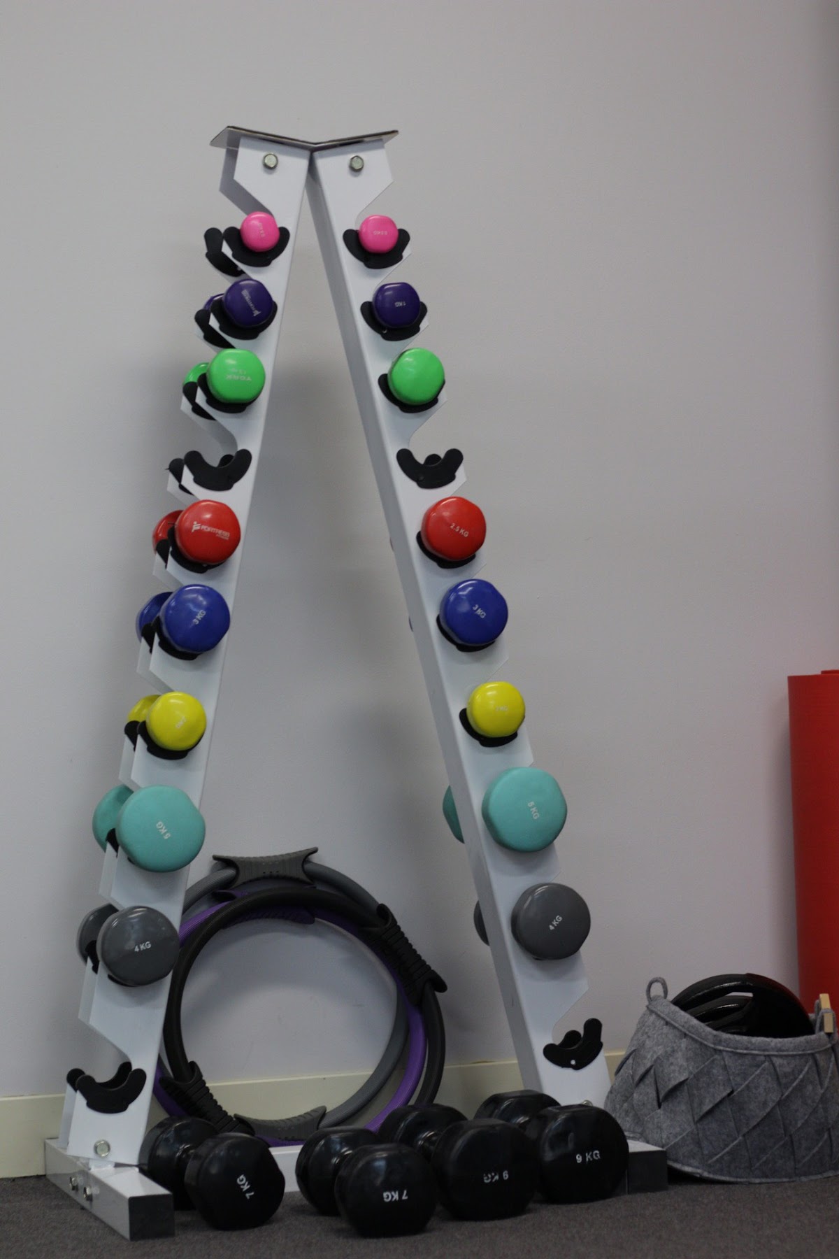 A close-up shot of a dumbbell rack and yoga mats in a gym setting, showcasing various weights and equipment.