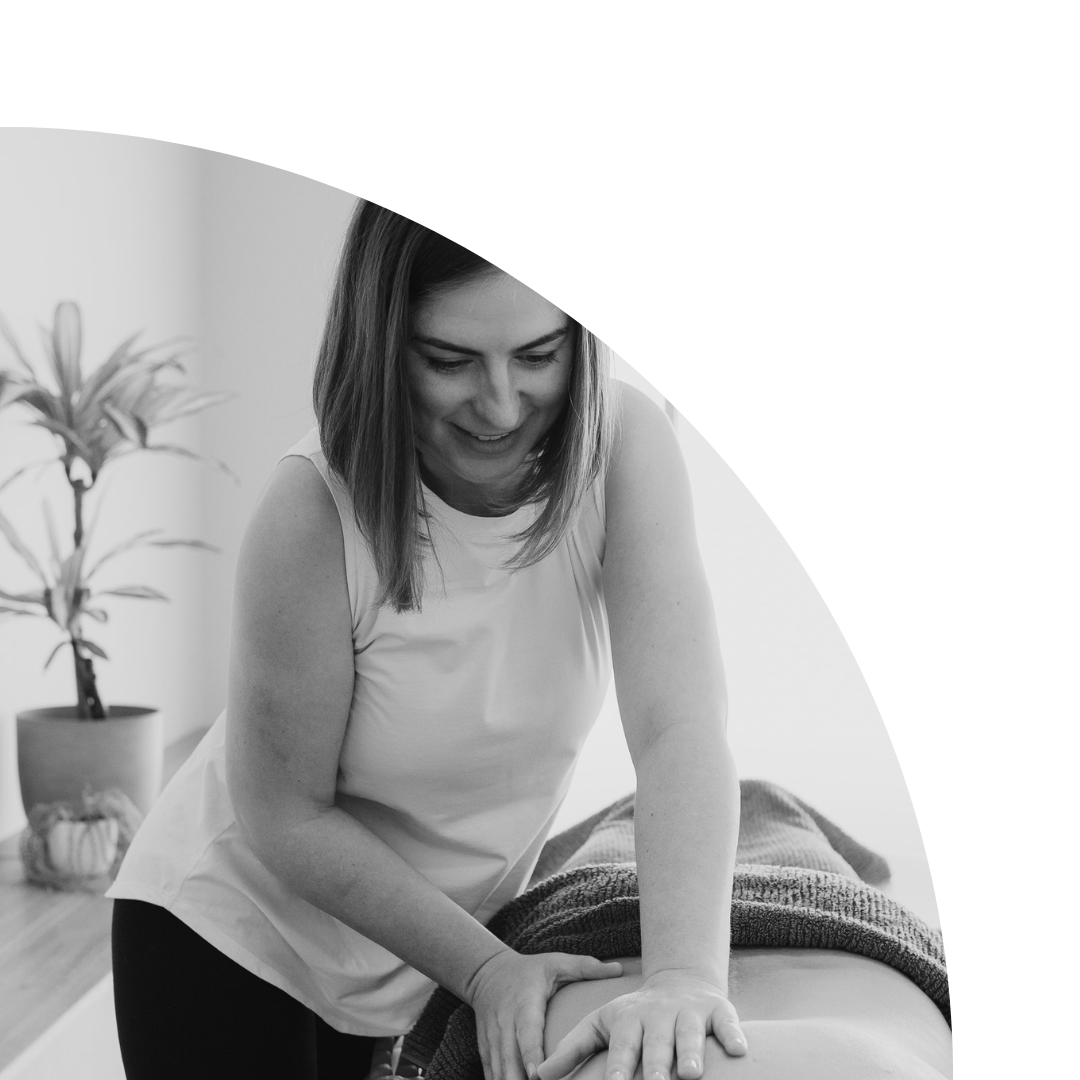 A female trainer is shown performing a massage on a client in a calming, minimalist setting.