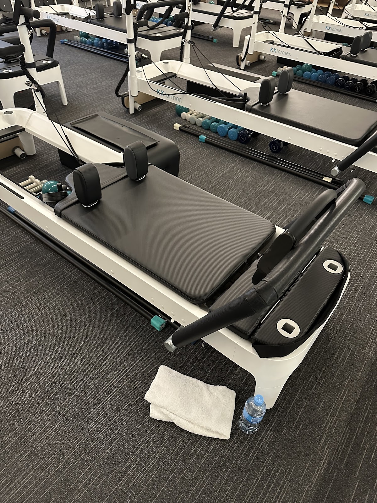 The photo showcases a clean and minimalist interior of a fitness studio featuring several reformer pilates machines.