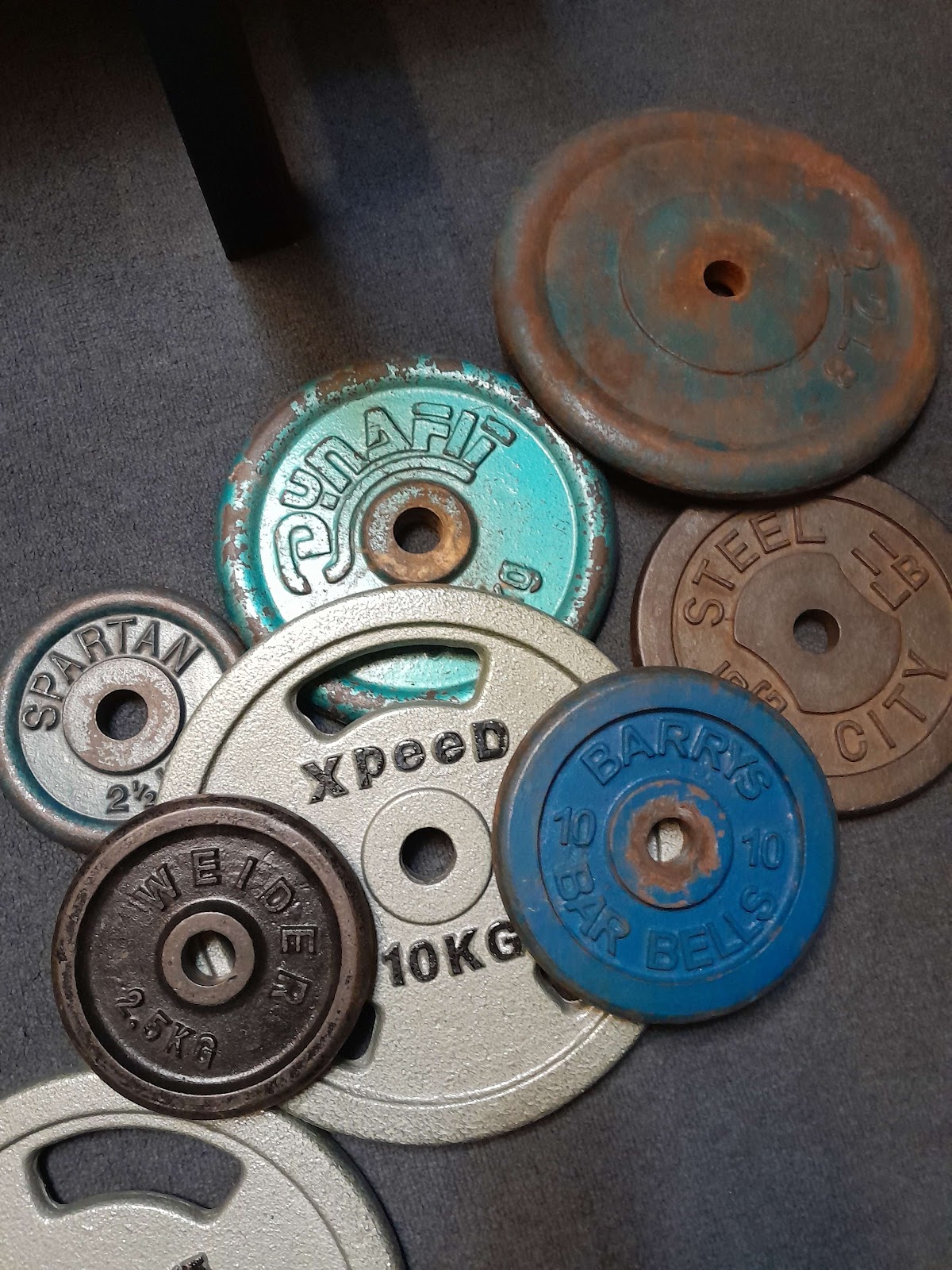 A close-up shot showcases a collection of weathered and vintage weight plates with various markings and weights.