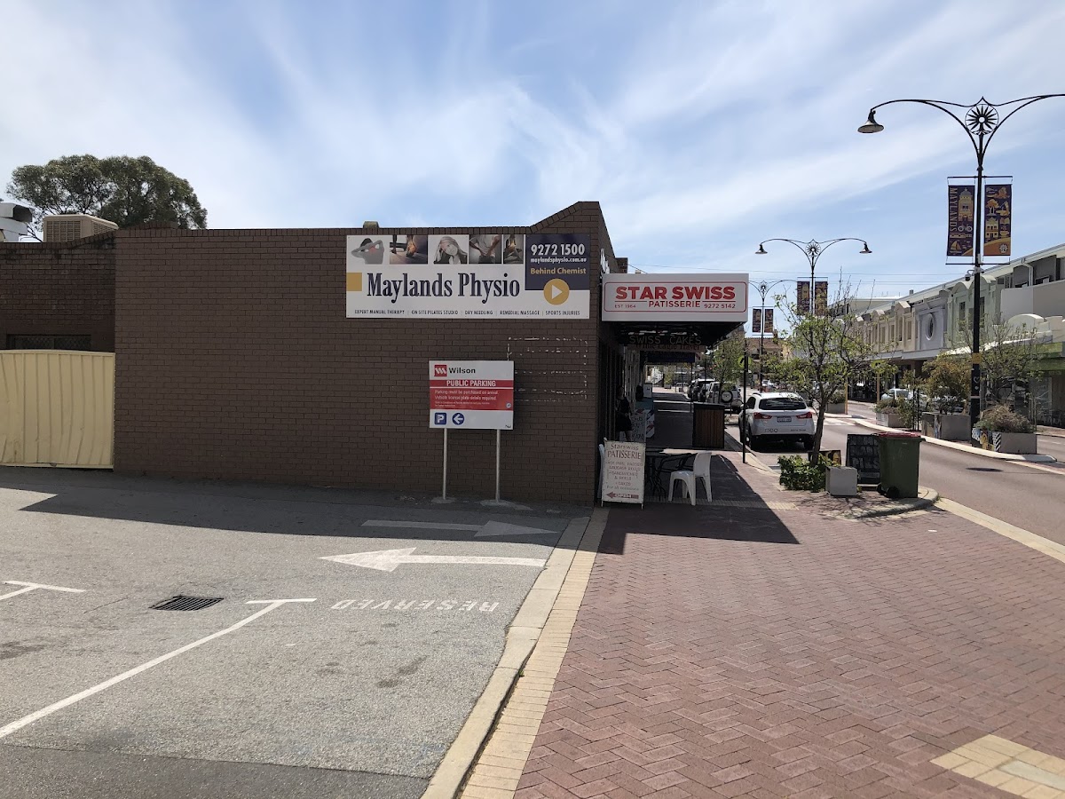 This photo shows the exterior of Maylands Physio, a physiotherapy clinic located on a street with parking and nearby businesses.