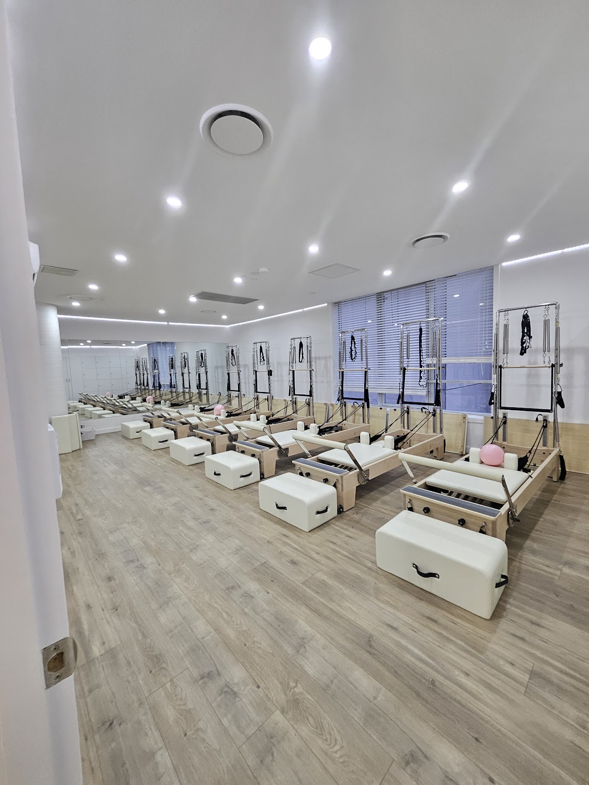 The photo shows a bright and clean studio with multiple reformer pilates machines lined up, suggesting a dedicated space for pilates training.