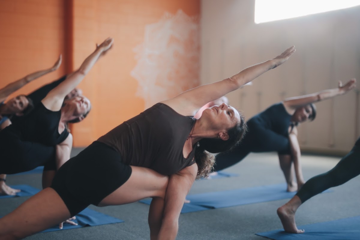 A group of people are practicing yoga in a studio with an orange wall.