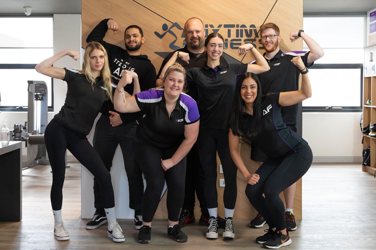 A group of trainers from a fitness business pose for a promotional photo showcasing their strength and team spirit.