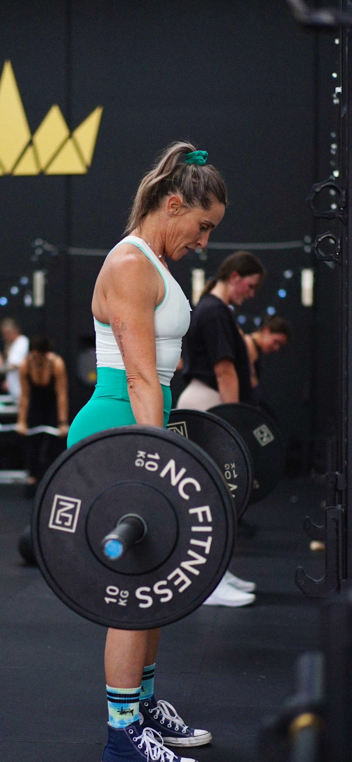 A woman is performing a squat with a barbell in a dimly lit industrial gym.