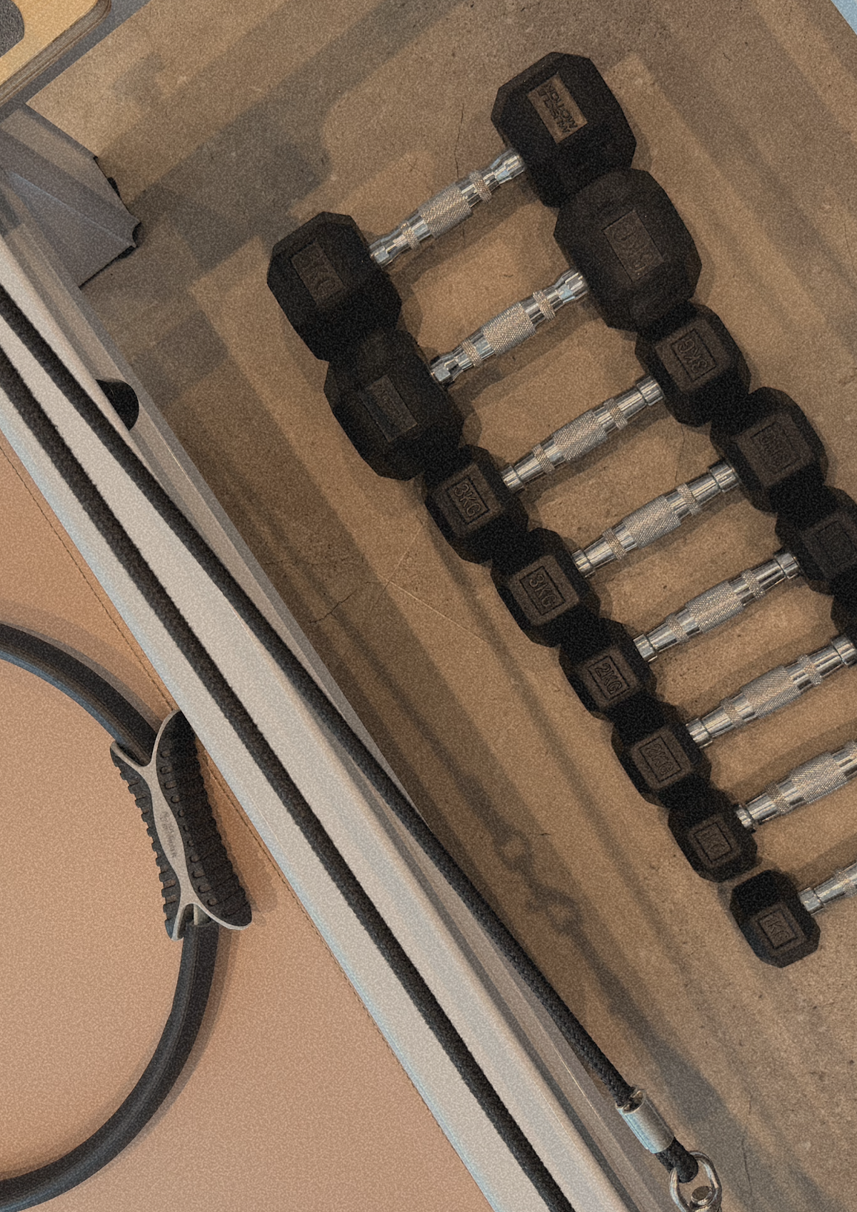 A close-up shot shows a rack of dumbbells in what appears to be a clean and minimalist fitness setting.