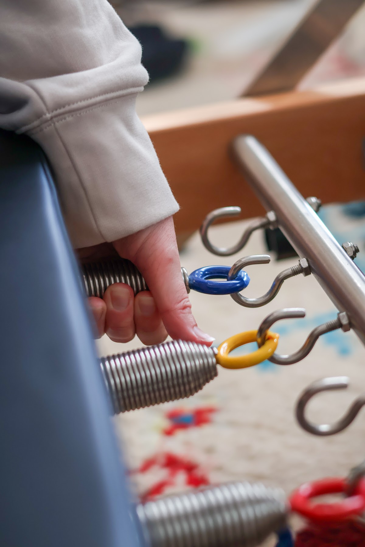 A close-up shot shows a hand interacting with the springs and hardware of a Pilates reformer machine.