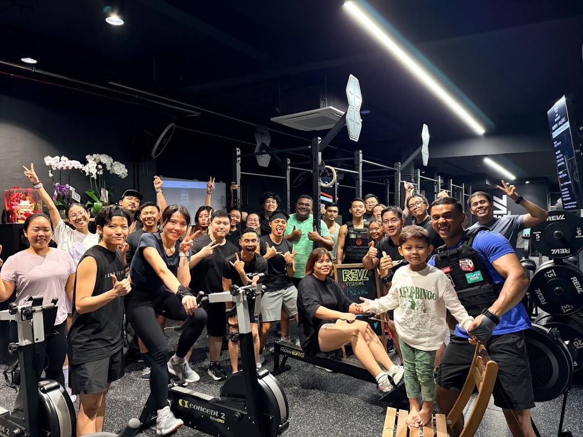 A group of people are celebrating after a rowing class in a brightly lit gym.