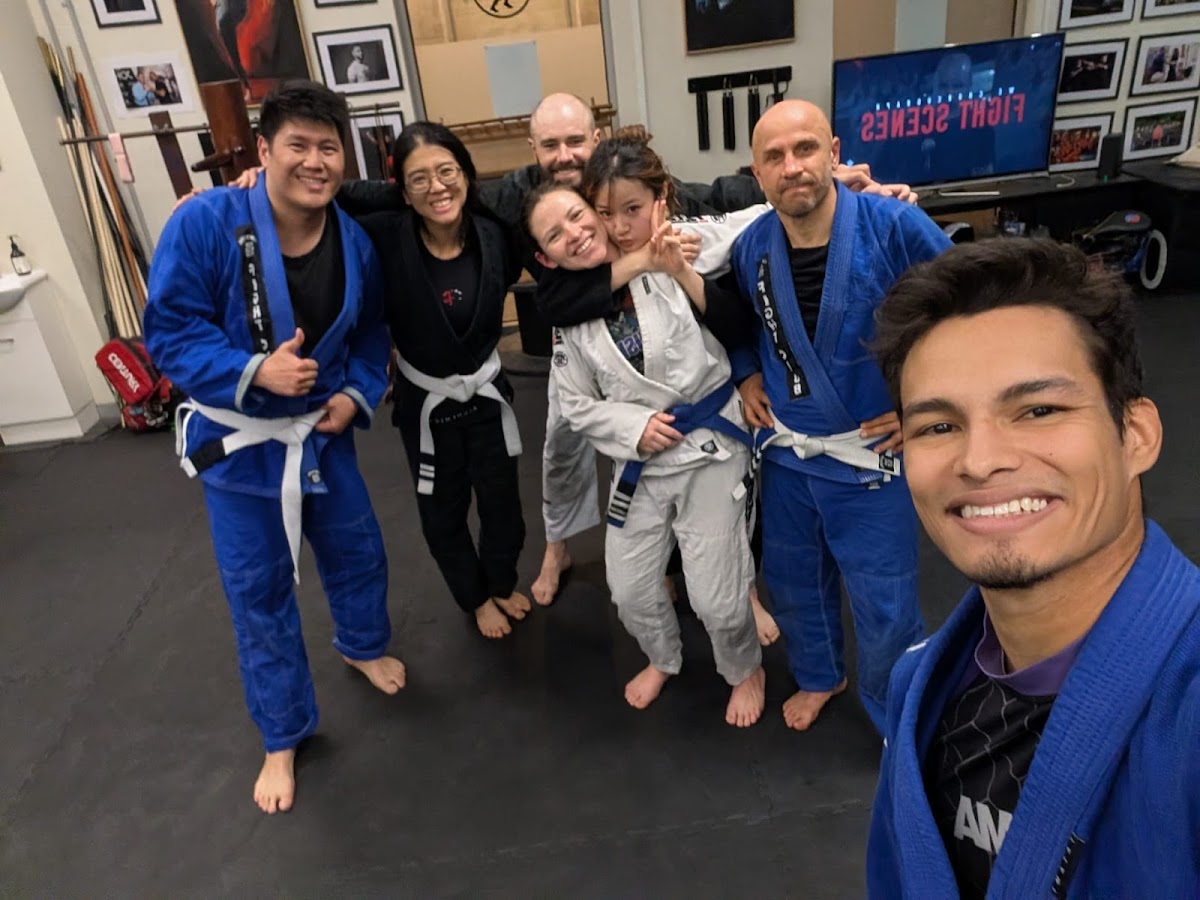 A group of people in Jiu-Jitsu gis are posing for a photo inside what appears to be a martial arts training facility.