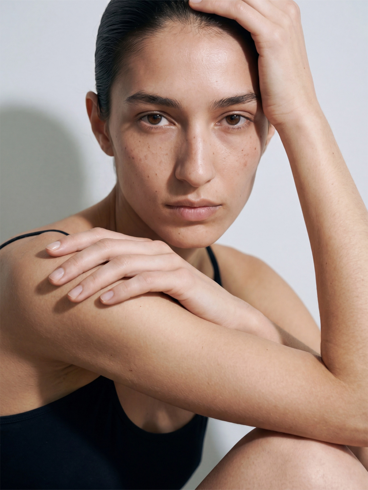 Close-up portrait of a fair-skinned woman with straight platinum blonde hair, natural freckles, and a neutral expression.