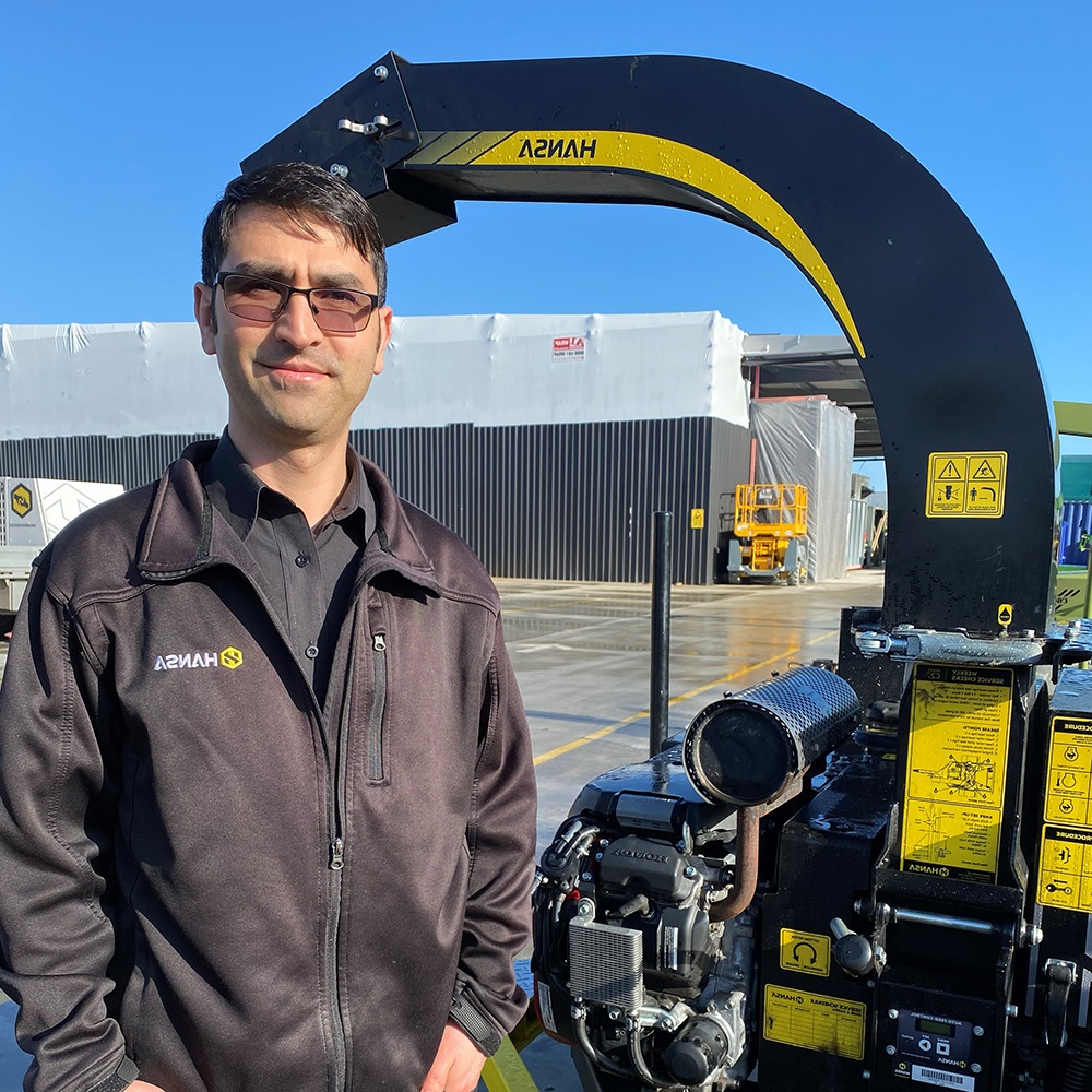 Hansa staff member standing next to a black and yellow commercial chipper