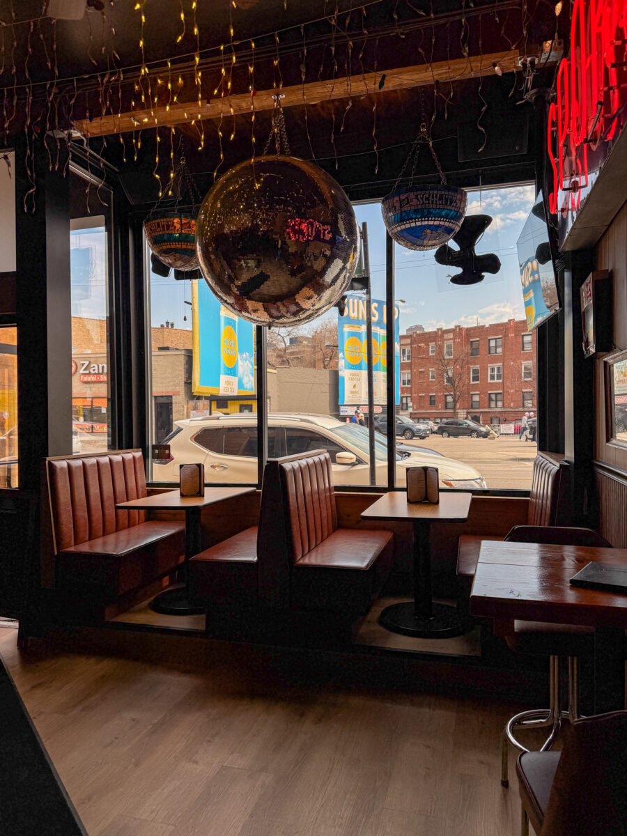 sports bar booth seating with large front windows, disco ball, string lights, and street views near Wrigley Field.