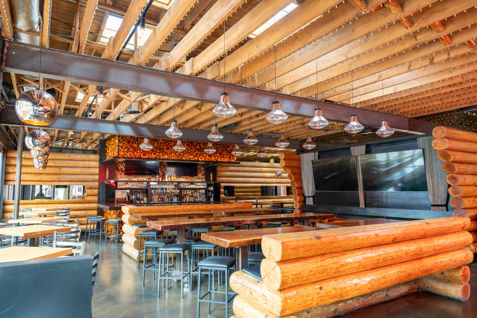 slide 1 of 5 - Indoor log cabin style restaurant and bar area, high top booth seating