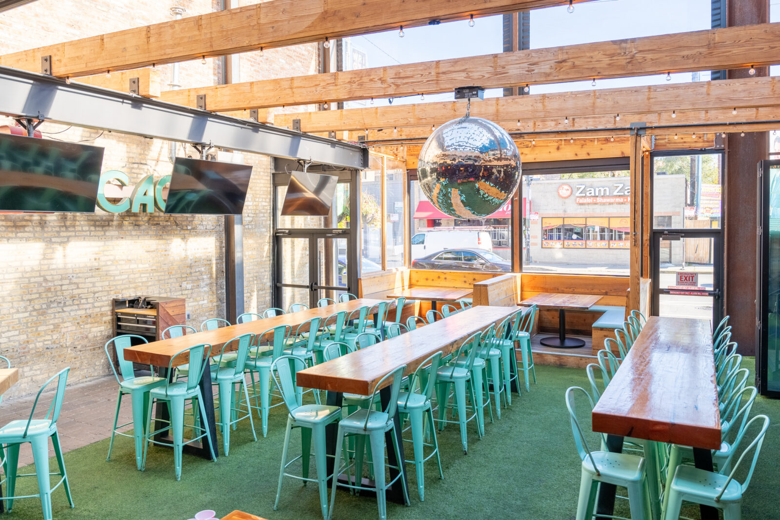 slide 1 of 2 - Open air patio with long communal high top tables and large disco ball