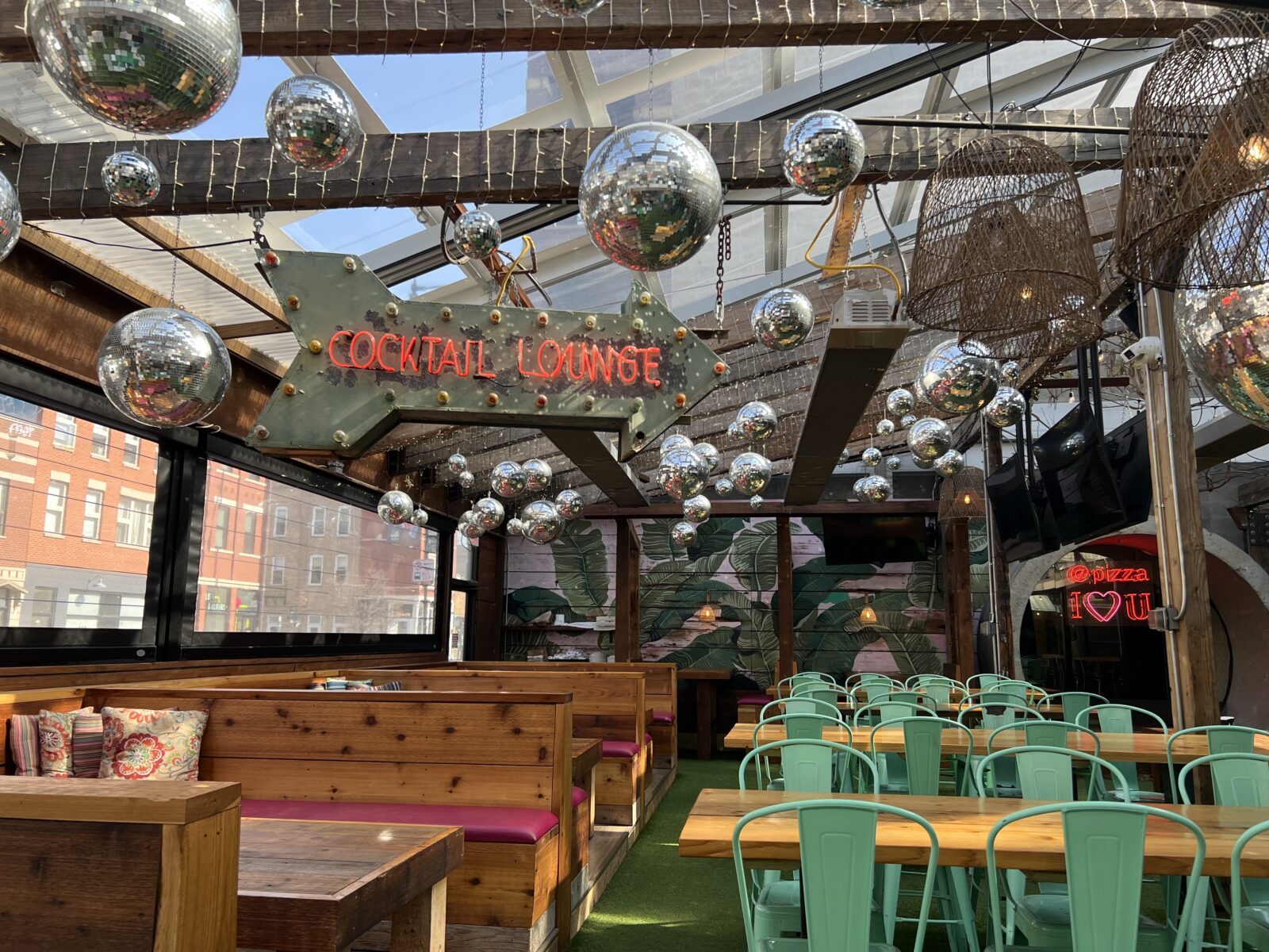 front patio of paradise park with booths for seating and other tables. cocktail lounge sign is hanging above with disco balls.