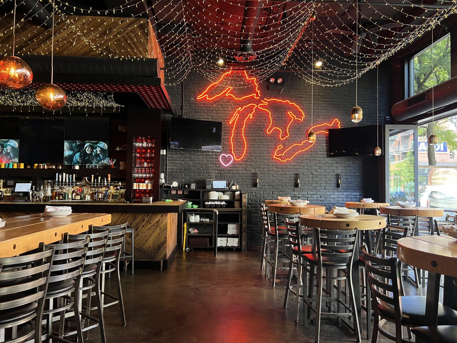 inside bar featuring communal tables and lake michigan neon