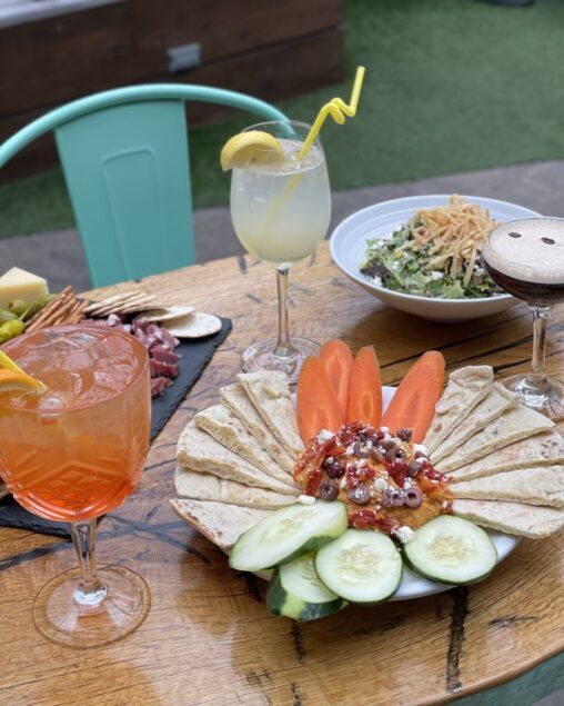 happy hour spread with spritzes, hummus and salad