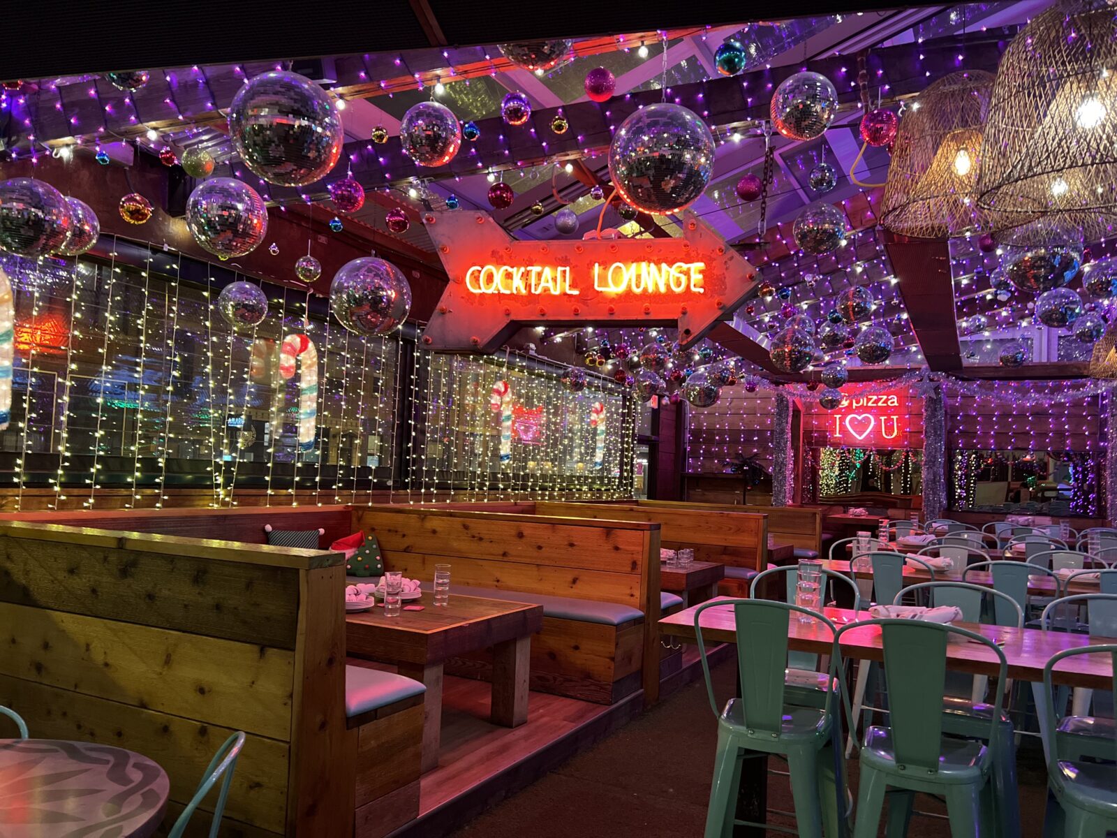 covered patio decorated for christmas with cocktail lounge sign lit up and disco balls reflecting the light