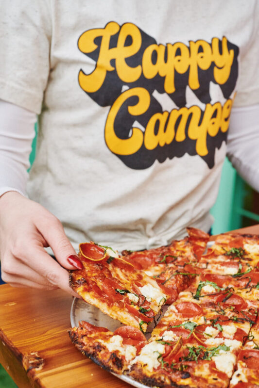 Someone grabbing a piece of pizza available during Las Vegas Restaurant Week.