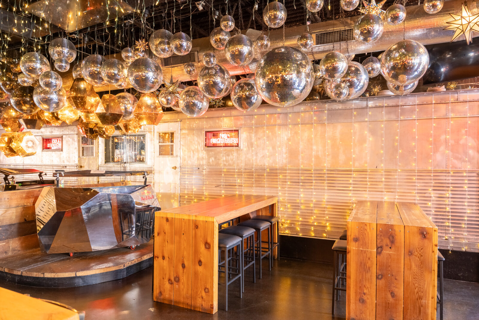 slide 2 of 3 - Dj booth with disco balls above, long communal tables for seating