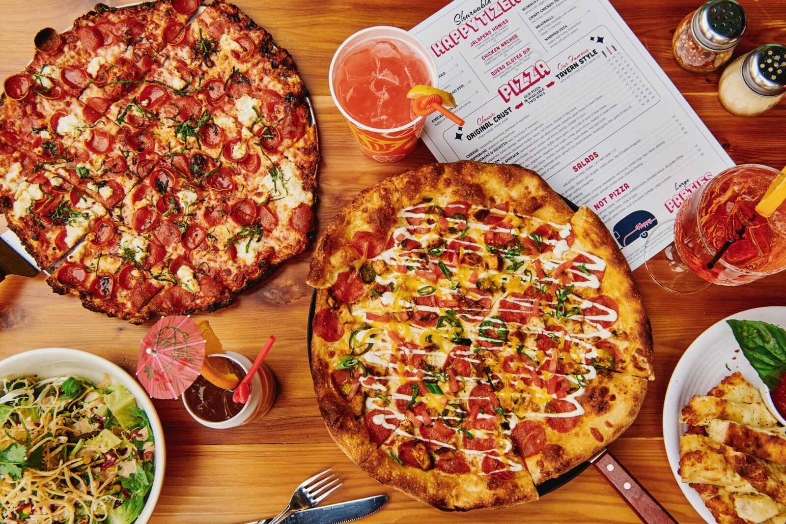 Spread of Happy Camper pizza, salad, and cocktails available on Mother's Day