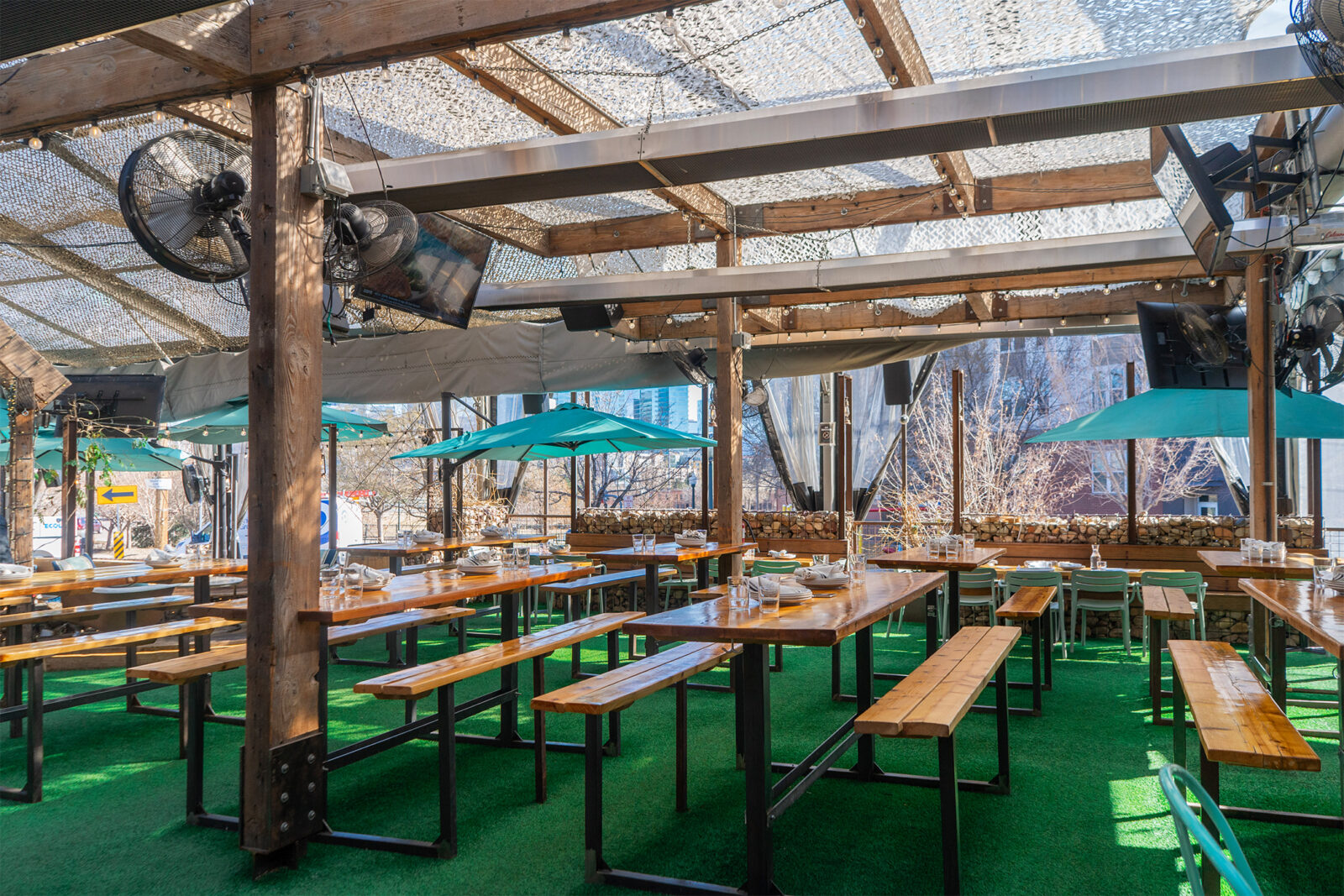 slide 3 of 4 - Patio seating with hightop picnic tables, low tops and blue umbrellas