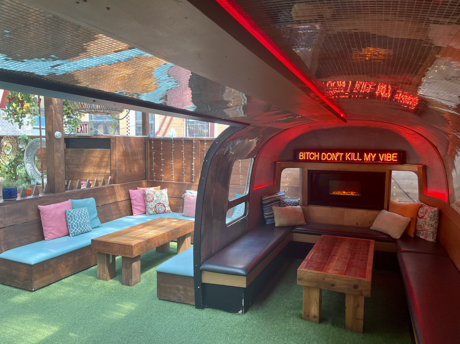 slide 2 of 2 - Inside of an airstream camper, colorful booth style seating and neon sign