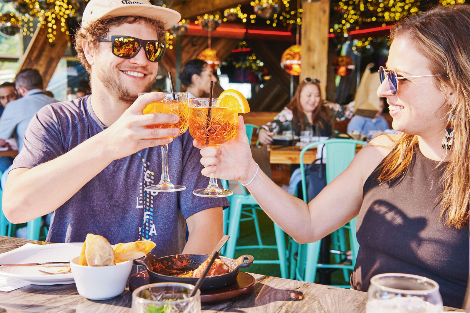 A man and woman cheersing their Aperol Spritz, available on Memorial Day