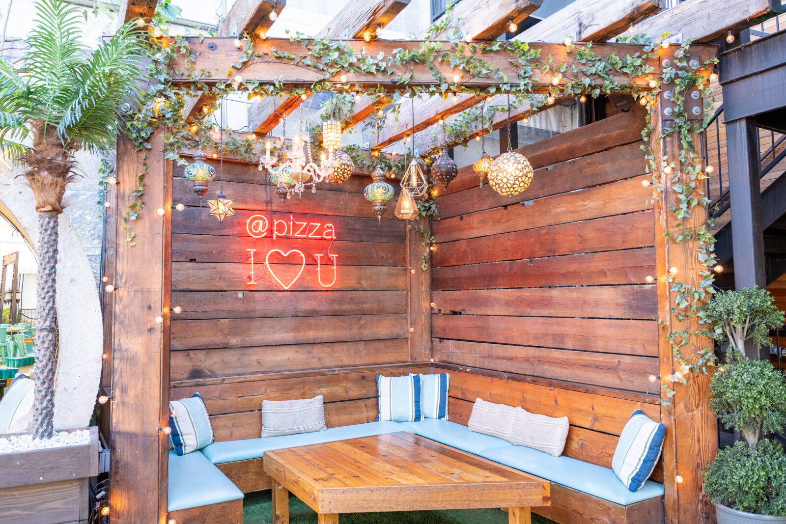slide 1 of 2 - Cabana booth seating with chandeliers and neon sign